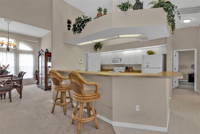 235 Tournament Rd, Rotonda West, FL 33947 - kitchen featuring a chandelier, white appliances, a peninsula, a high ceiling, and a breakfast bar area