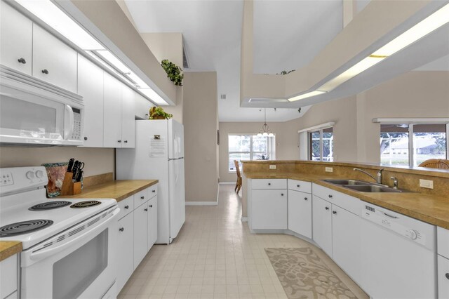 235 Tournament Rd, Rotonda West, FL 33947 - kitchen featuring white appliances, white cabinets, a sink, baseboards, and a notable chandelier