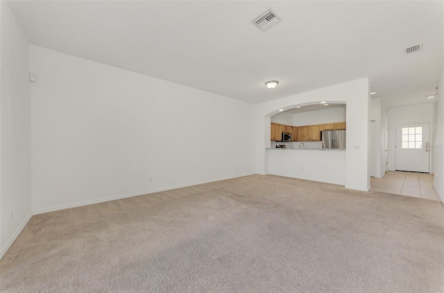 1156 Jonah Dr, North Port, FL 34289 - unfurnished living room with light carpet, baseboards, arched walkways, and visible vents