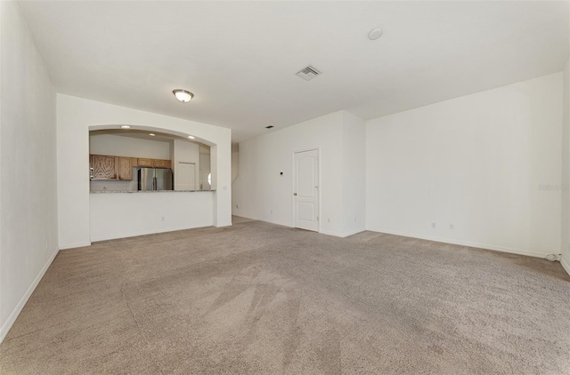 1156 Jonah Dr, North Port, FL 34289 - unfurnished living room with arched walkways, carpet flooring, visible vents, and baseboards