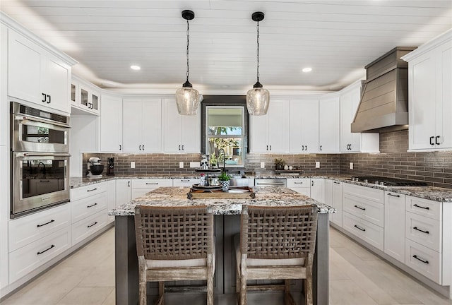 310 Severin Rd SE, Port Charlotte, FL 33952 - kitchen with white cabinets, stainless steel appliances, a kitchen bar, decorative backsplash, and a kitchen island