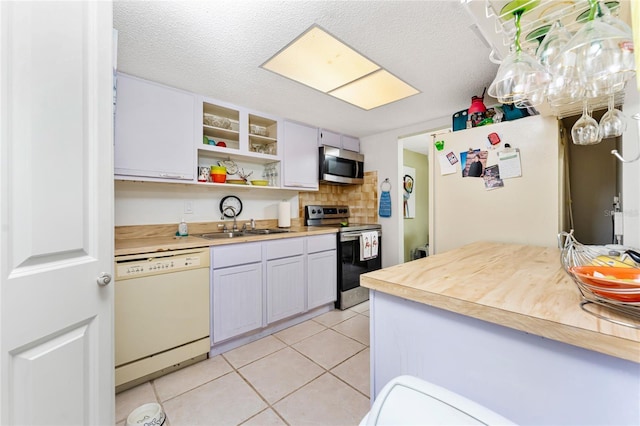 4022 Beaver Ln Unit 500C, Port Charlotte, FL 33952 - kitchen with stainless steel appliances, a sink, light tile patterned flooring, open shelves, and a textured ceiling