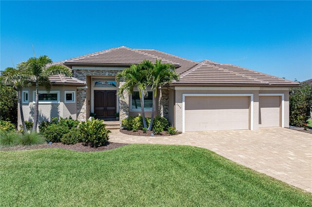 view of front of house featuring stucco siding, an attached garage, a tiled roof, and decorative driveway