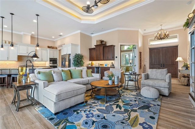living area featuring ornamental molding, a high ceiling, a chandelier, and light wood-type flooring