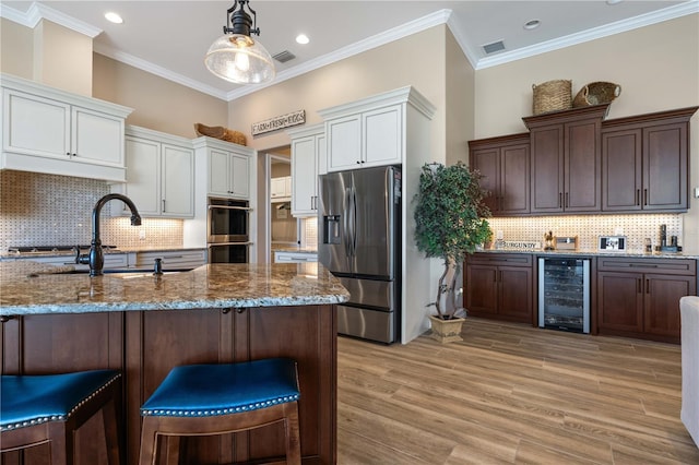 kitchen featuring light stone countertops, beverage cooler, stainless steel appliances, visible vents, and white cabinets