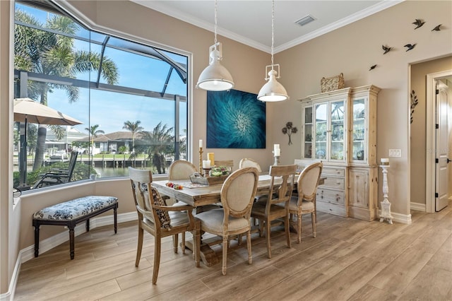 dining space with baseboards, visible vents, light wood-style floors, and crown molding
