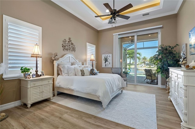 bedroom featuring access to exterior, visible vents, light wood-style floors, and a raised ceiling