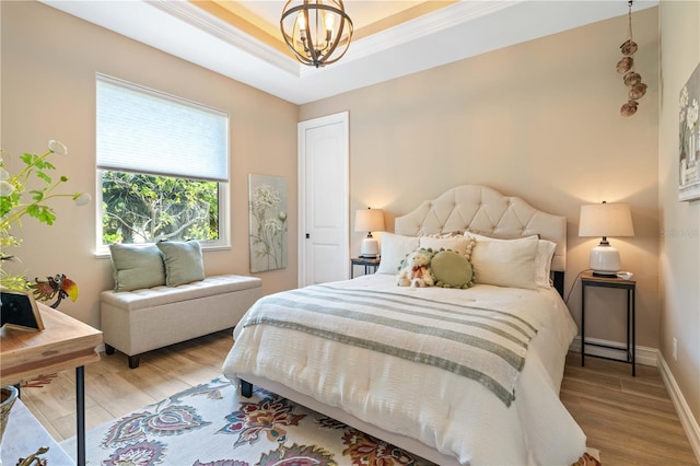 bedroom featuring a chandelier, a raised ceiling, baseboards, and light wood finished floors