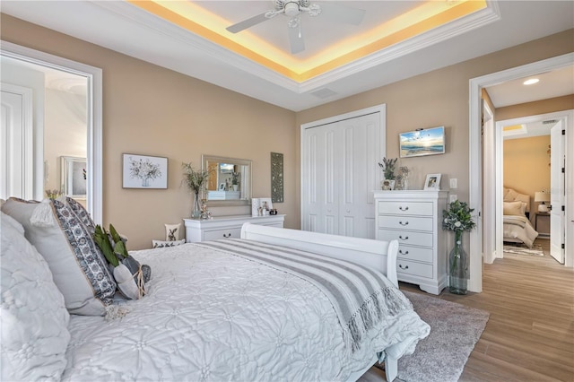 bedroom featuring a closet, ceiling fan, wood finished floors, recessed lighting, and a tray ceiling