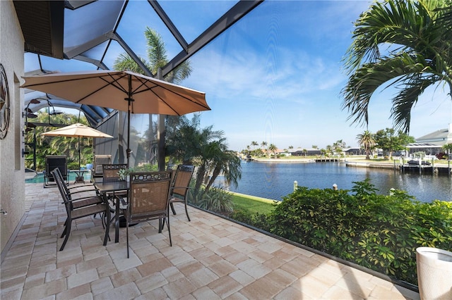 view of patio / terrace featuring outdoor dining space, a lanai, and a water view