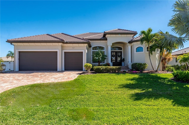 347 Portofino Dr, Punta Gorda, FL 33950 - mediterranean / spanish-style home featuring an attached garage, stucco siding, a tile roof, decorative driveway, and a front lawn