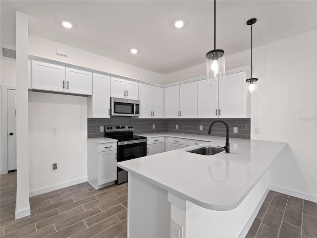 14449 Appleton Blvd, Port Charlotte, FL 33981 - kitchen featuring appliances with stainless steel finishes, a peninsula, white cabinetry, backsplash, and recessed lighting