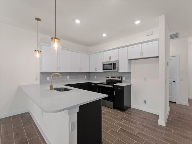 14449 Appleton Blvd, Port Charlotte, FL 33981 - kitchen featuring stainless steel appliances, white cabinetry, a peninsula, light countertops, and wood finish floors