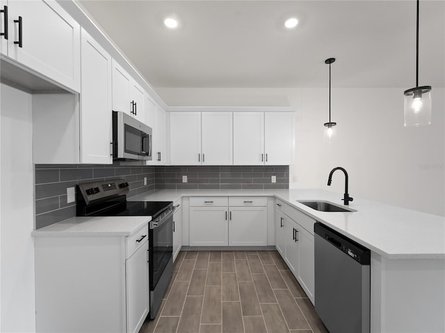 14449 Appleton Blvd, Port Charlotte, FL 33981 - kitchen with appliances with stainless steel finishes, a peninsula, tasteful backsplash, white cabinets, and recessed lighting