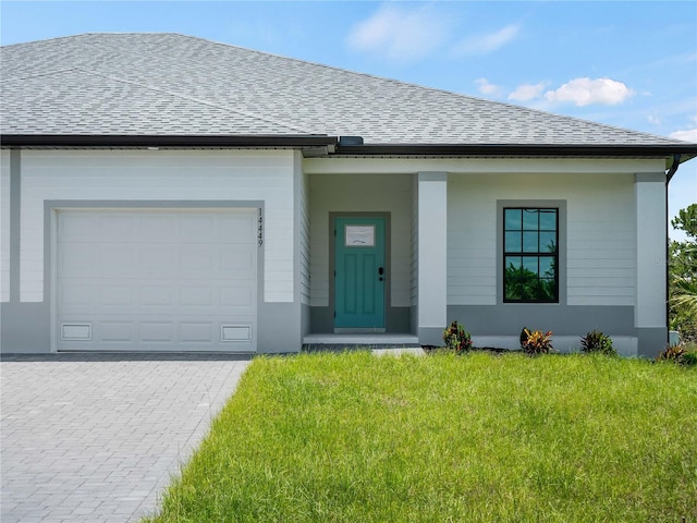14449 Appleton Blvd, Port Charlotte, FL 33981 - view of front of house featuring a shingled roof, an attached garage, a front lawn, and decorative driveway