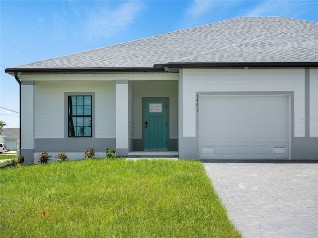 14449 Appleton Blvd, Port Charlotte, FL 33981 - view of front of home featuring an attached garage, a shingled roof, a front lawn, and decorative driveway