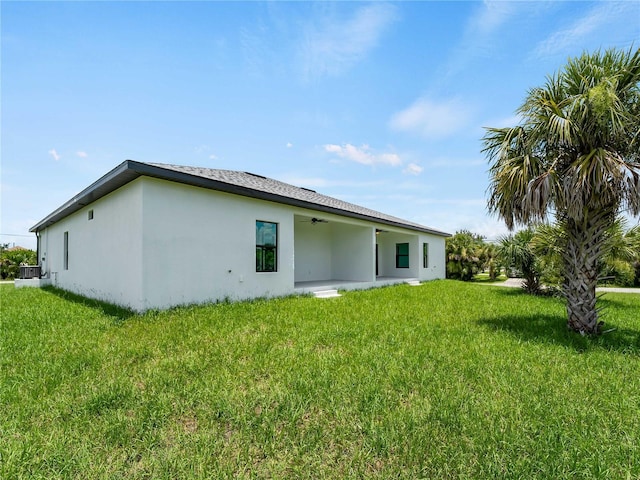 14449 Appleton Blvd, Port Charlotte, FL 33981 - back of house featuring a ceiling fan, a yard, and stucco siding