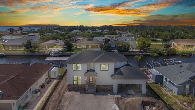 aerial view at dusk with a water view and a residential view