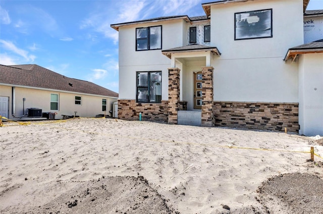 view of front of house with stone siding, central AC unit, and stucco siding