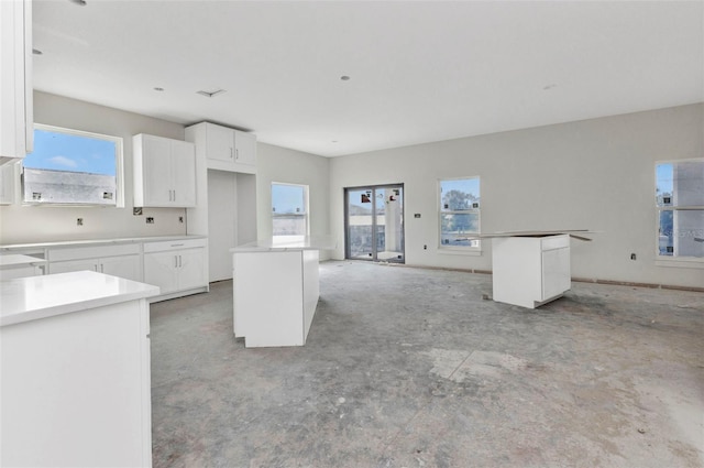 kitchen featuring open floor plan, concrete flooring, a center island, and white cabinetry