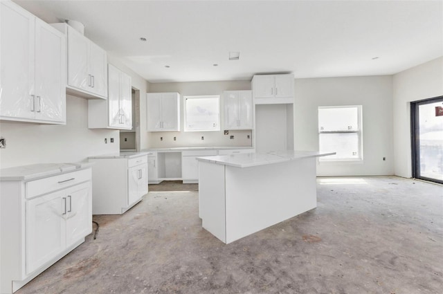 kitchen with white cabinets, concrete floors, and a kitchen island