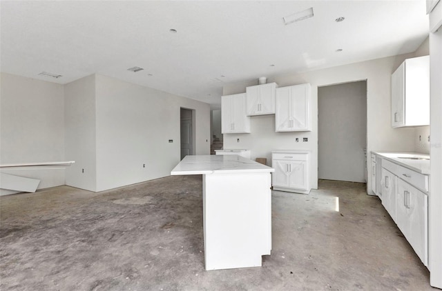 kitchen with white cabinets, a kitchen island, and concrete floors