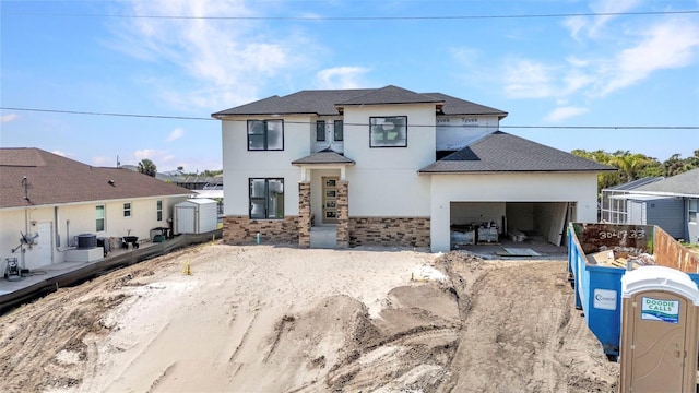 view of front facade with central AC, stone siding, fence, stucco siding, and a storage unit