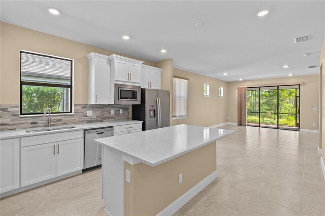 1352 Raspberry Dr, North Port, FL 34289 - kitchen with stainless steel appliances, backsplash, a kitchen island, recessed lighting, and white cabinets