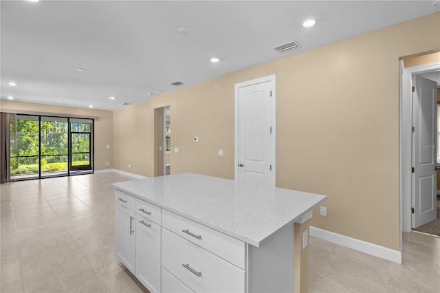 1352 Raspberry Dr, North Port, FL 34289 - kitchen featuring a kitchen island, light stone counters, recessed lighting, open floor plan, and white cabinets