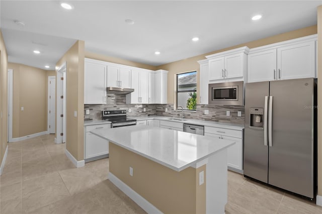 1352 Raspberry Dr, North Port, FL 34289 - kitchen featuring stainless steel appliances, tasteful backsplash, white cabinets, a kitchen island, and under cabinet range hood