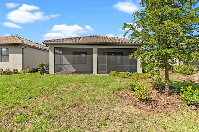 1352 Raspberry Dr, North Port, FL 34289 - back of property with a sunroom, a tile roof, a lawn, and stucco siding
