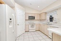 23482 Moreland Ave, Port Charlotte, FL 33954 - kitchen featuring light tile patterned floors, light countertops, light brown cabinetry, and white appliances