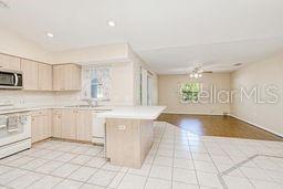 23482 Moreland Ave, Port Charlotte, FL 33954 - kitchen with light countertops, stove, stainless steel microwave, light brown cabinetry, and a peninsula