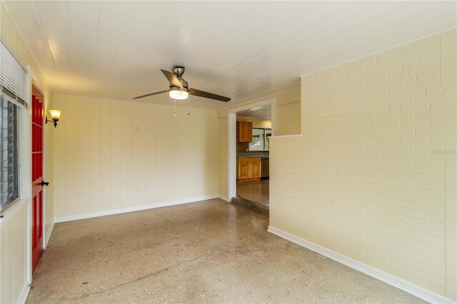 217 Palm Ave E, Nokomis, FL 34275 - empty room with a ceiling fan, speckle patterned floor, brick wall, and baseboards