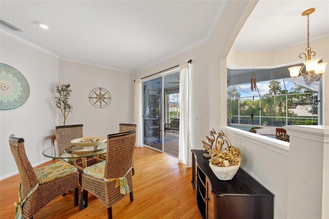 dining space featuring visible vents, baseboards, a notable chandelier, light wood-type flooring, and crown molding