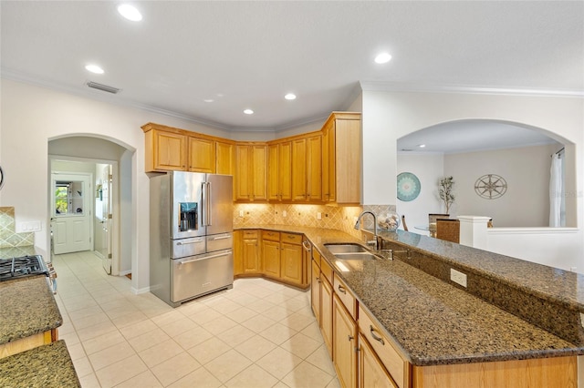 kitchen with visible vents, a sink, high end fridge, and decorative backsplash