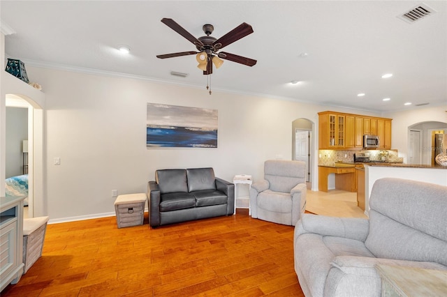 living room featuring arched walkways, a ceiling fan, and visible vents