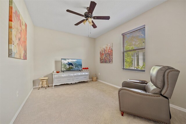 living area featuring carpet floors, baseboards, and a ceiling fan