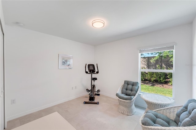 exercise room with light tile patterned flooring and baseboards