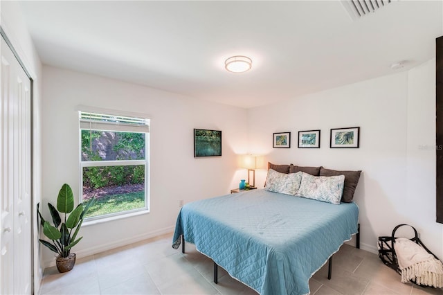 bedroom featuring light tile patterned flooring, baseboards, visible vents, and a closet