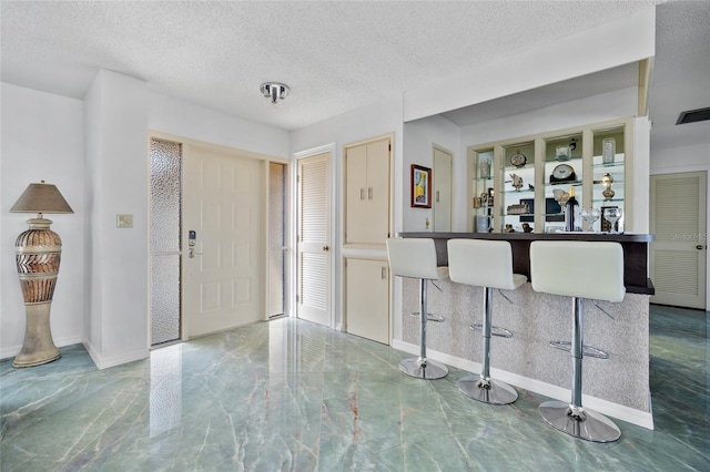 foyer with marble finish floor, baseboards, and a textured ceiling