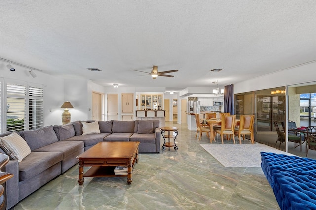 living room featuring track lighting, a textured ceiling, ceiling fan, and visible vents