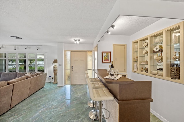 entryway with baseboards, visible vents, rail lighting, and a textured ceiling
