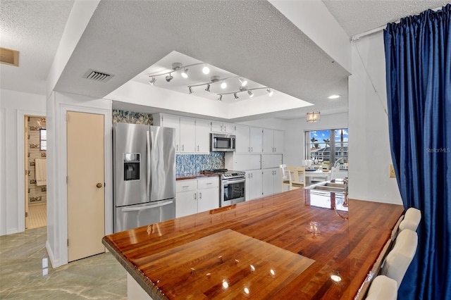 kitchen featuring a textured ceiling, visible vents, tasteful backsplash, appliances with stainless steel finishes, and white cabinetry
