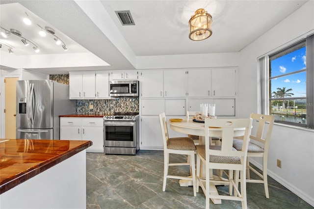 kitchen featuring white cabinets, visible vents, butcher block counters, tasteful backsplash, and appliances with stainless steel finishes