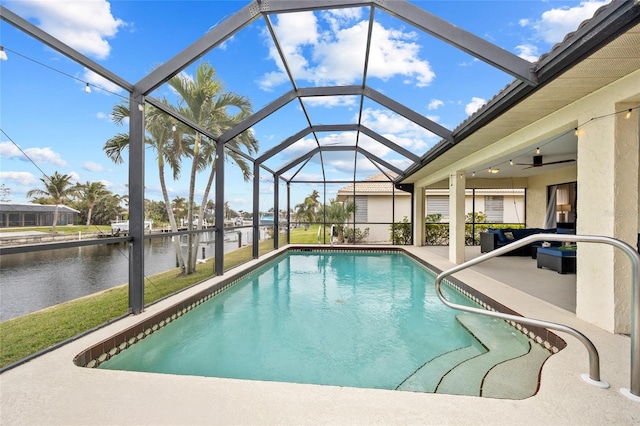 outdoor pool with a patio, a water view, a ceiling fan, and a lanai