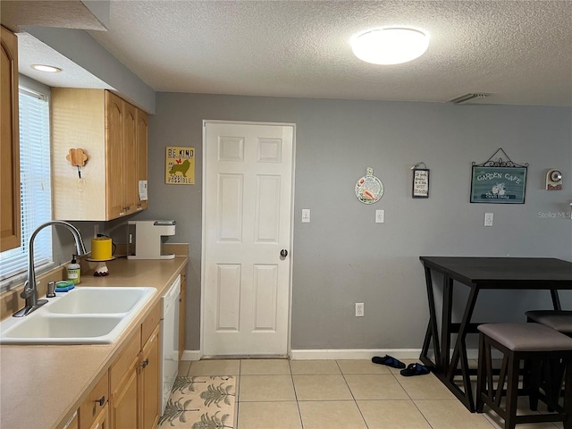 kitchen with light tile patterned flooring, a sink, dishwasher, plenty of natural light, and visible vents