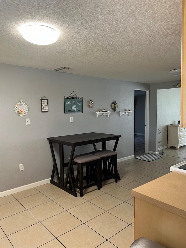 dining area with light tile patterned flooring, baseboards, a textured ceiling, and visible vents