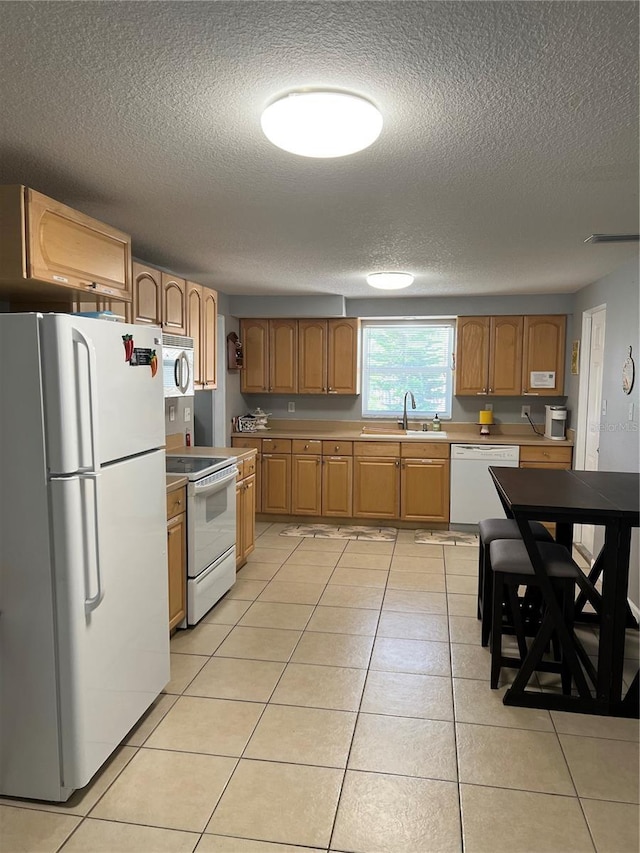 kitchen with light countertops, a sink, a textured ceiling, light tile patterned floors, and white appliances