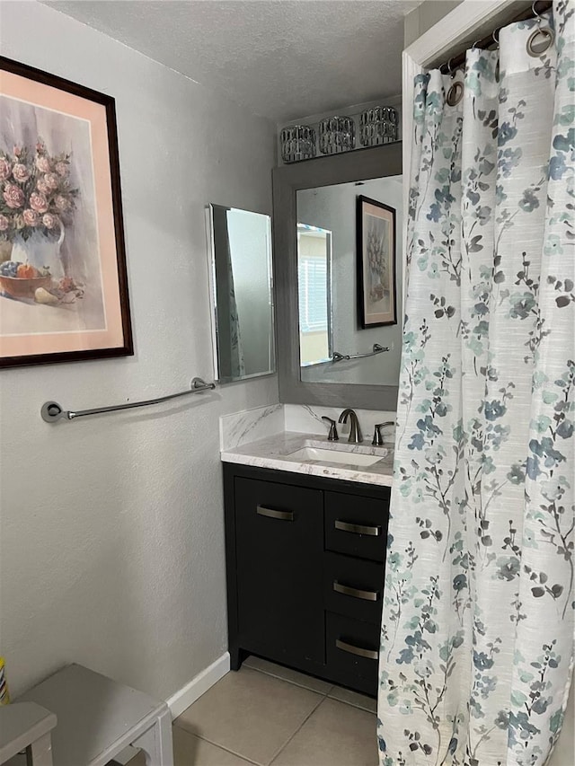 full bathroom with tile patterned floors, a shower with shower curtain, vanity, a textured ceiling, and baseboards